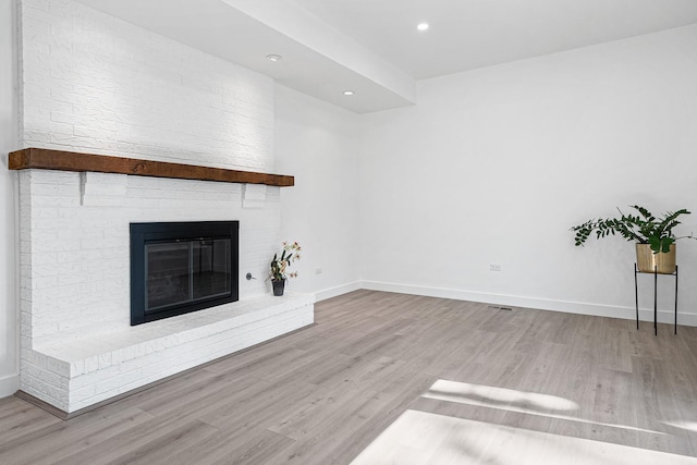 unfurnished living room featuring wood finished floors, a fireplace, baseboards, and recessed lighting
