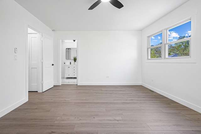 unfurnished bedroom featuring baseboards, light wood finished floors, connected bathroom, and ceiling fan