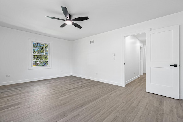 empty room featuring light wood-type flooring, a ceiling fan, and baseboards