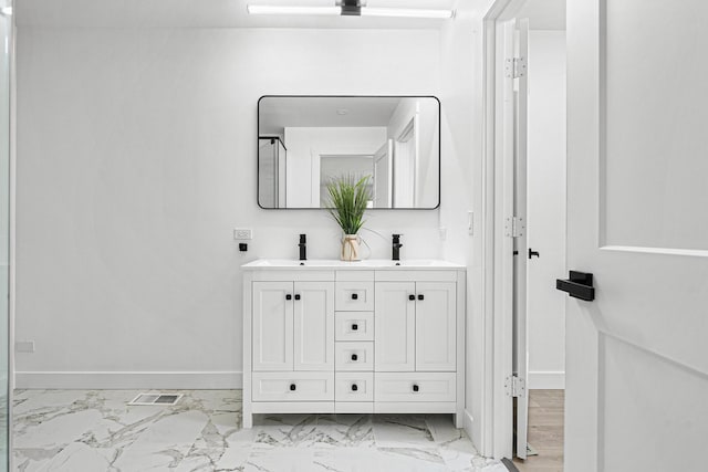 bathroom with baseboards, marble finish flooring, and double vanity