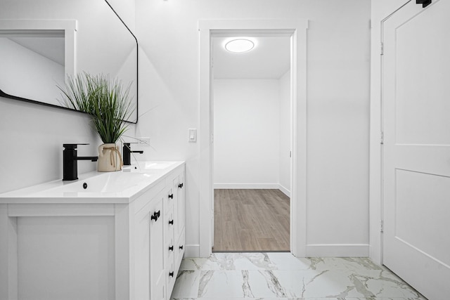 bathroom with marble finish flooring, double vanity, and baseboards