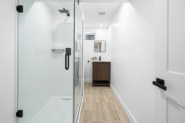 full bath featuring vanity, a shower stall, wood finished floors, and baseboards