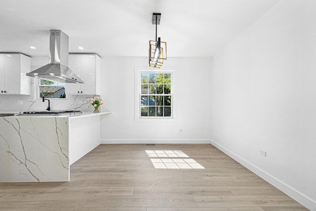 unfurnished dining area with baseboards, light wood finished floors, and recessed lighting