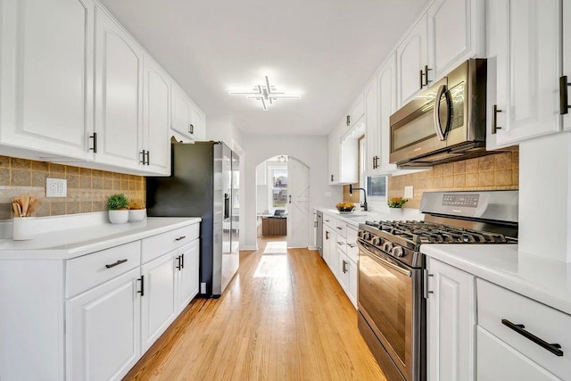 12540 S Tripp Ave, Alsip, IL 60803 - kitchen featuring stainless steel appliances, arched walkways, light wood-style flooring, light countertops, and white cabinetry