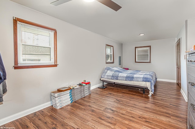 bedroom with baseboards, multiple windows, a ceiling fan, and wood finished floors