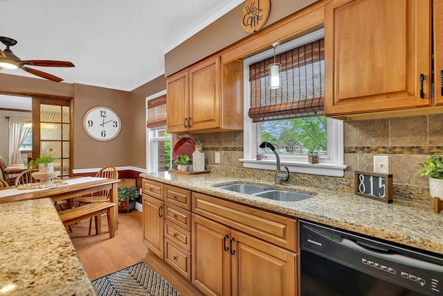 kitchen featuring a sink, black dishwasher, a ceiling fan, plenty of natural light, and light stone countertops