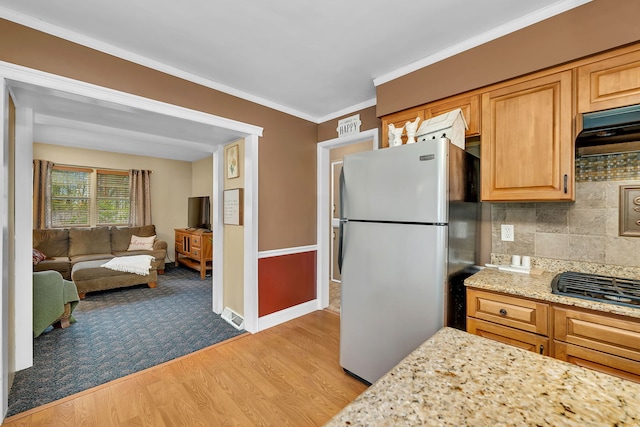 kitchen with light wood-style flooring, freestanding refrigerator, open floor plan, crown molding, and decorative backsplash