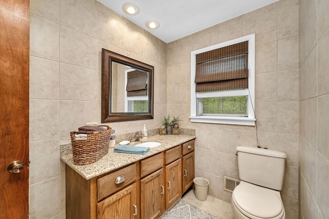 bathroom with tile walls, toilet, visible vents, and vanity