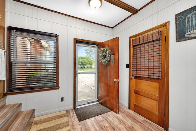 foyer with ornamental molding, baseboards, and light wood-type flooring