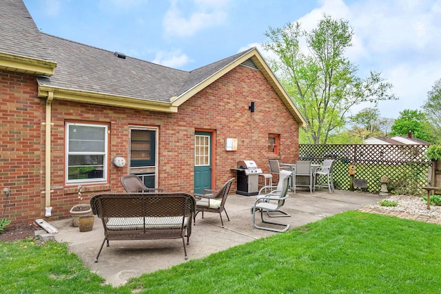 rear view of property with a yard, fence, a shingled roof, brick siding, and an outdoor living space