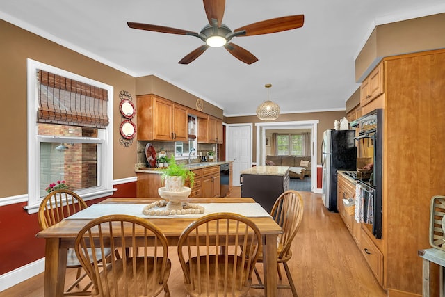 dining area with crown molding, light wood-style floors, baseboards, and ceiling fan