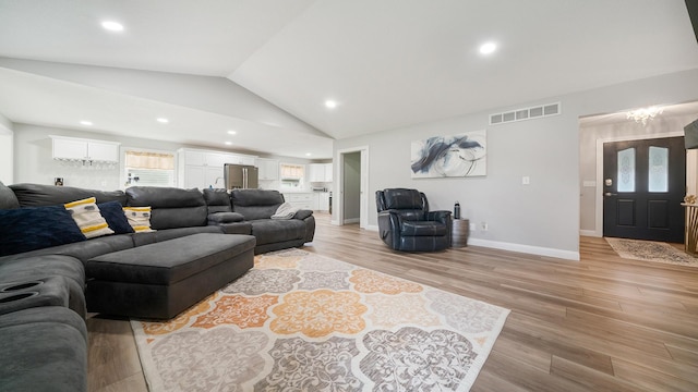 living room with vaulted ceiling, light wood-style flooring, visible vents, and recessed lighting