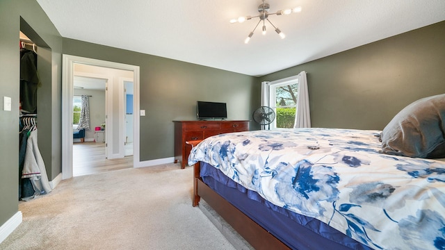 carpeted bedroom featuring a notable chandelier and baseboards