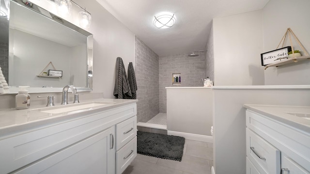 bathroom with a sink, walk in shower, two vanities, and tile patterned floors