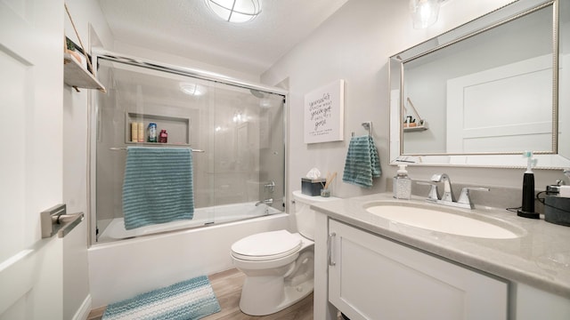 full bathroom with toilet, wood finished floors, vanity, a textured ceiling, and shower / bath combination with glass door