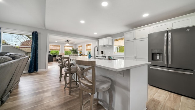 kitchen with a breakfast bar area, stainless steel fridge, open floor plan, light countertops, and recessed lighting