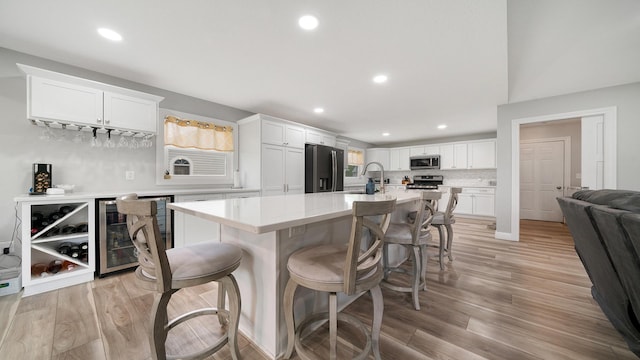 kitchen featuring white cabinets, appliances with stainless steel finishes, a breakfast bar area, and wine cooler
