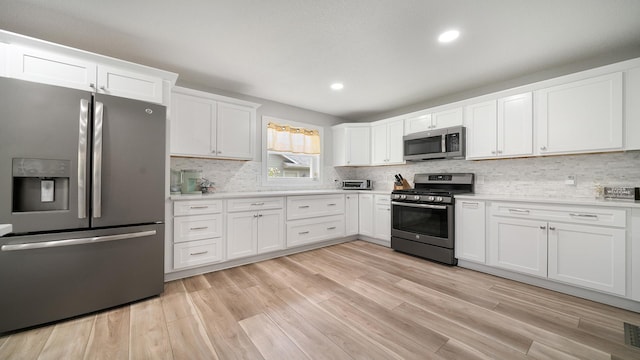 kitchen featuring stainless steel appliances, white cabinetry, light countertops, and backsplash