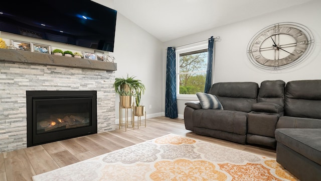 living area with baseboards, a fireplace, wood finished floors, and vaulted ceiling