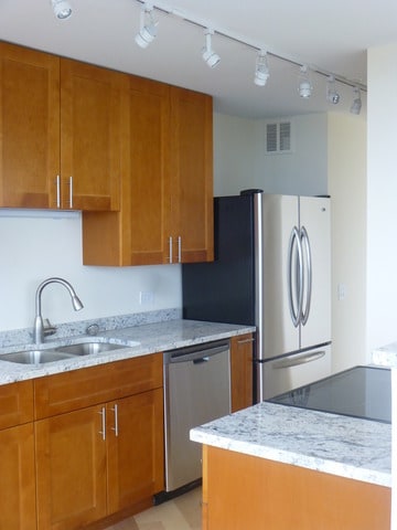 kitchen with brown cabinetry, visible vents, appliances with stainless steel finishes, a sink, and track lighting