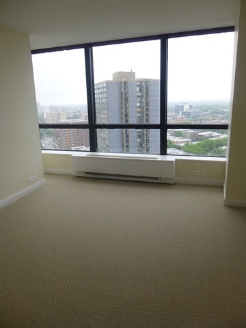 carpeted empty room featuring a view of city and baseboards