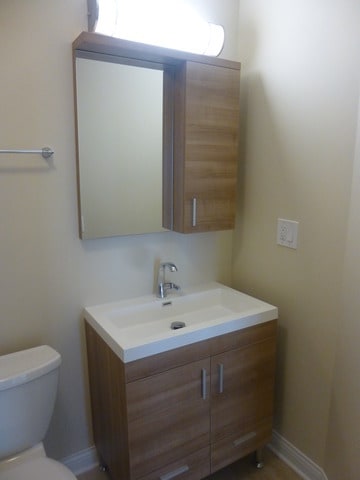 half bath with vanity, baseboards, and toilet