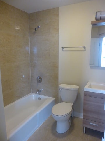 full bath with shower / bath combination, vanity, tile patterned flooring, and toilet