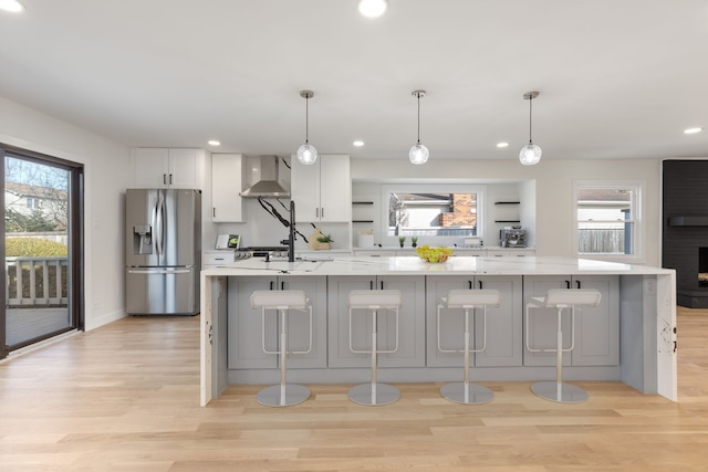 617 Sara Ln, Naperville, IL 60565 - kitchen with stainless steel refrigerator with ice dispenser, a healthy amount of sunlight, wall chimney range hood, and light wood-type flooring