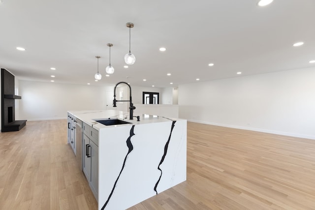 617 Sara Ln, Naperville, IL 60565 - kitchen with an island with sink, light countertops, a sink, light wood-style flooring, and decorative light fixtures