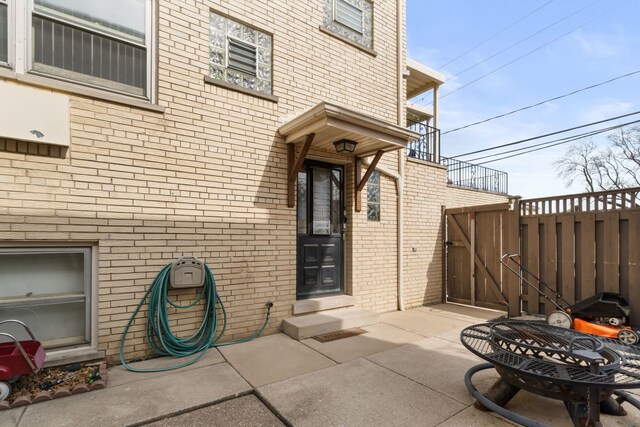 doorway to property with brick siding, fence, and a patio