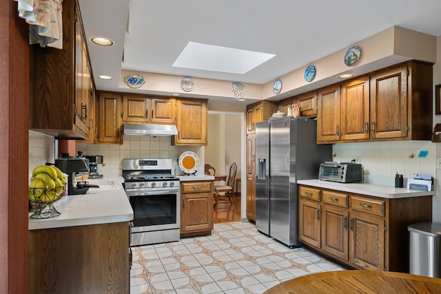 6338 Parkwood Ct, Oak Forest, IL 60452 - kitchen with appliances with stainless steel finishes, a skylight, under cabinet range hood, light countertops, and backsplash