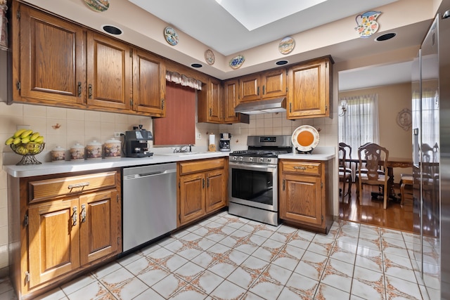 6338 Parkwood Ct, Oak Forest, IL 60452 - kitchen with appliances with stainless steel finishes, light countertops, under cabinet range hood, and brown cabinetry