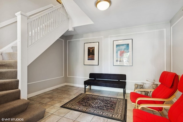 sitting room featuring baseboards and stairs