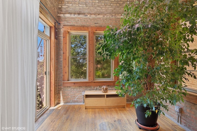 bathroom with brick wall and hardwood / wood-style flooring