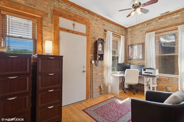 office with light wood finished floors, brick wall, ceiling fan, and visible vents