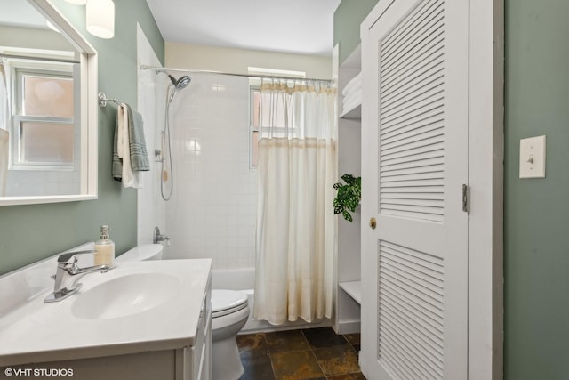 full bath with toilet, shower / tub combo with curtain, vanity, and stone finish floor