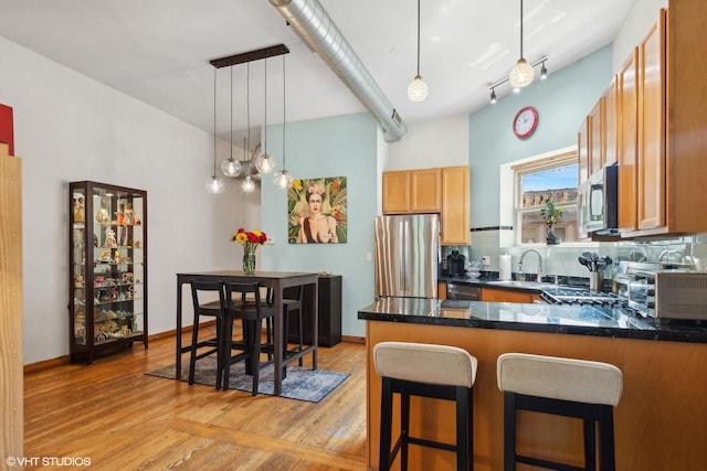 kitchen featuring a toaster, a sink, a peninsula, stainless steel appliances, and tasteful backsplash