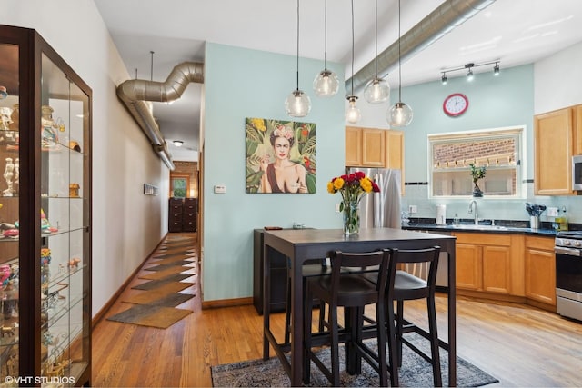 kitchen with backsplash, light wood-style floors, appliances with stainless steel finishes, and dark countertops