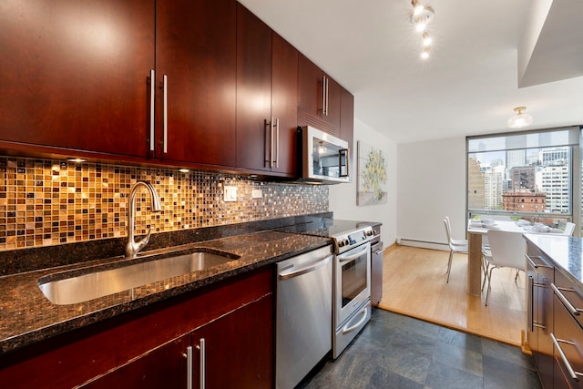 kitchen featuring tasteful backsplash, a sink, dark stone countertops, stainless steel appliances, and reddish brown cabinets