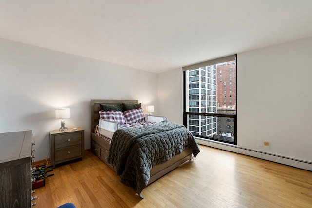 bedroom with baseboard heating, floor to ceiling windows, and wood finished floors