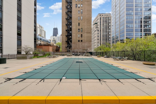 pool with a view of city, fence, and a patio area