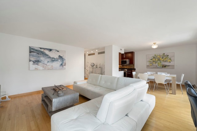 living area featuring baseboards, light wood-type flooring, and visible vents