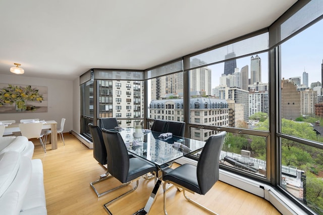 dining space with a baseboard heating unit, a city view, and wood finished floors