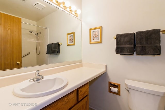 bathroom featuring toilet, vanity, and a shower