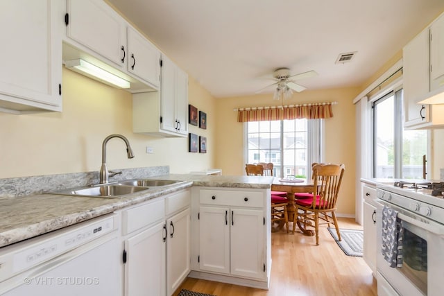 kitchen with white appliances, a sink, light wood-type flooring, and white cabinets