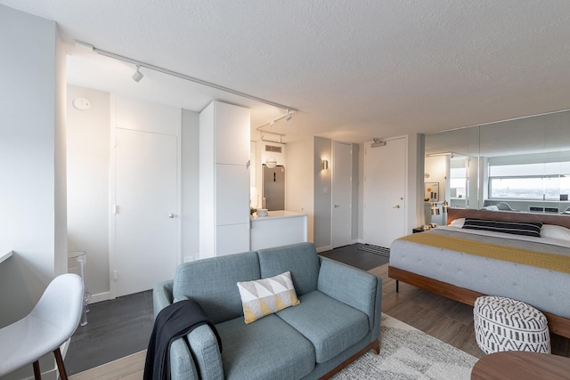 living area featuring rail lighting, wood finished floors, and a textured ceiling