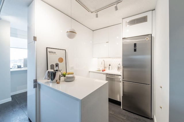 kitchen featuring appliances with stainless steel finishes, modern cabinets, a sink, white cabinets, and backsplash