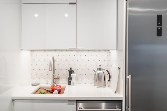 kitchen with high end fridge, white cabinets, tasteful backsplash, and light countertops