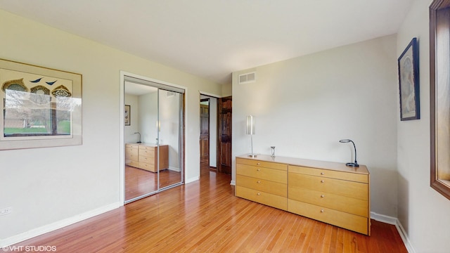 bedroom with baseboards, light wood finished floors, and visible vents