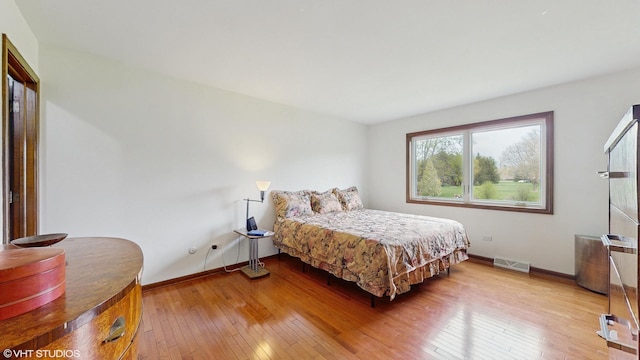 bedroom featuring visible vents, light wood-style flooring, and baseboards